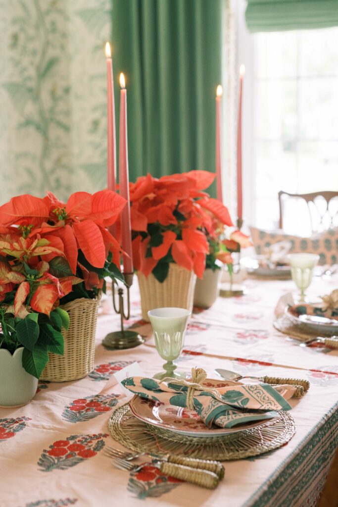 ambiance of lit holiday candles over a traditional holiday tablescape with a Indian block print tablecloth, flowers.