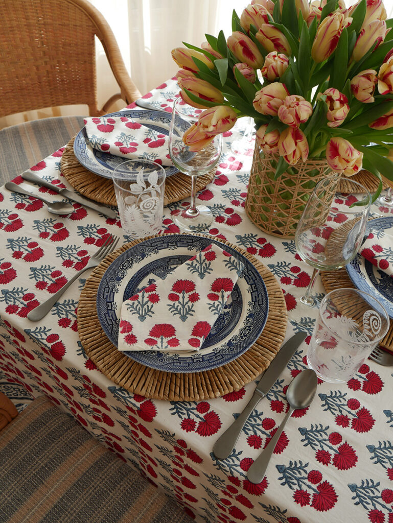 Hana block printed tablecloth and napkins with (delete with) showcasing classic red and blue floral prints on a vibrant table setting.